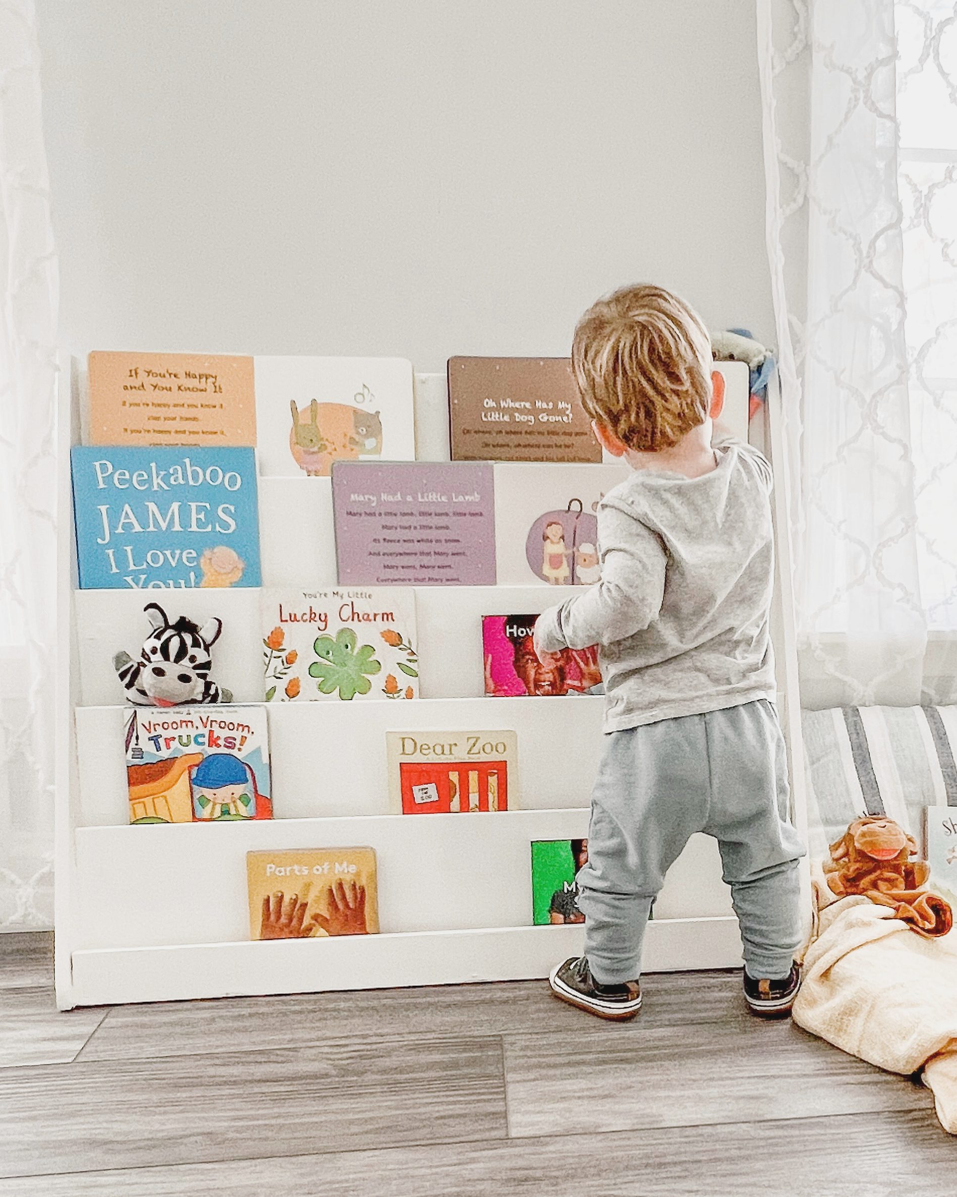 Young toddler at open face book case in play room