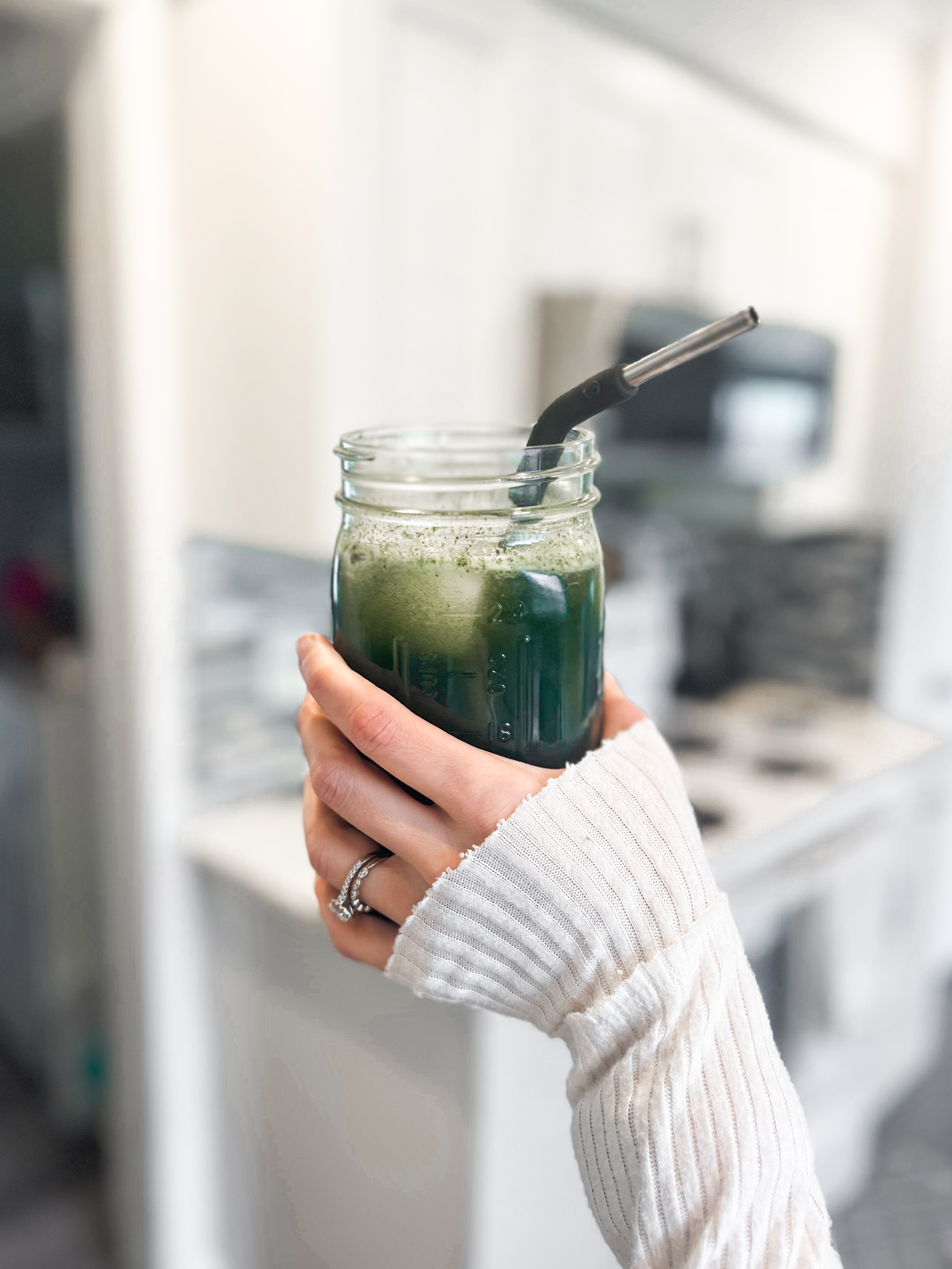 Arbonne's GreenSynergy Elixir - woman's hand holding mason jar with green drink and straw