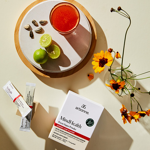 Flat Lay with Arbonne's Mind Health drink Box, packets, cup with red drink, and flowers